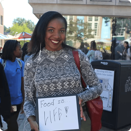 Volunteer holding up a board that says Food is Life